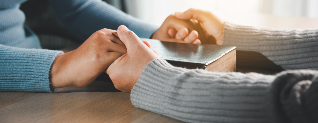 Hands offering prayer and spiritual support during pastoral counseling.